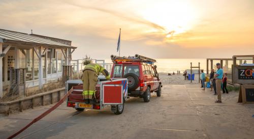 brandweerauto met aanhanger rijdt het strand op