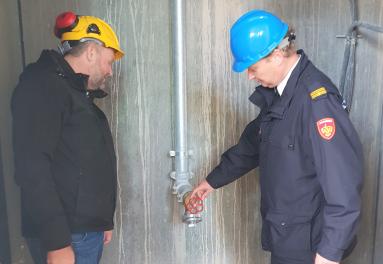 Twee mannen inspecteren een van de blusleidingen van de nieuwe woontoren